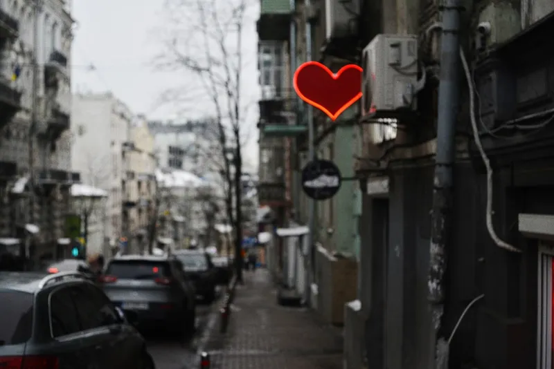 Red heart neon sign on a city street