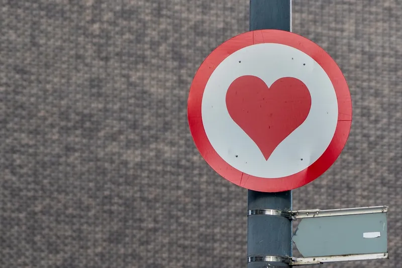 A red heart road sign on a post.